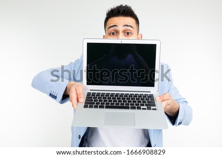 smiling young brunette man joyfully holds a laptop with blank for inserting a website page on a white background
