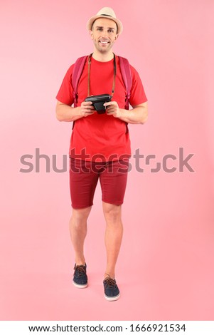 Male tourist with photo camera on color background