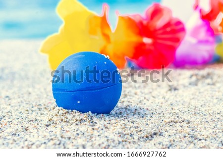 Close up of a ball and other beach objects on the sand in the summertime