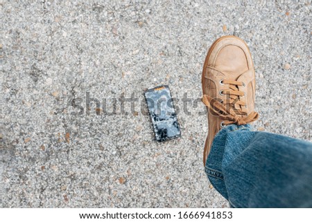 Man's shoe brutally stepping on and breaking his smartphone