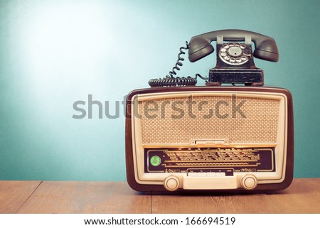 Retro old radio and telephone on a table front mint green background