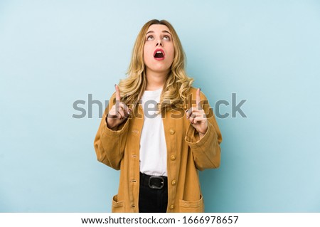 Young blonde pretty woman isolated pointing upside with opened mouth.
