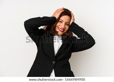 Middle age latin business woman isolated laughs joyfully keeping hands on head. Happiness concept.