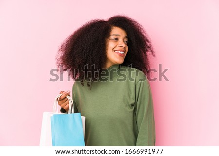 Young afro woman shopping isolated Young afro woman buying isolaYoung afro woman holding a roses isolated looks aside smiling, cheerful and pleasant.< mixto >