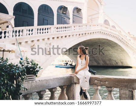 Young woman travel Italy. Vacation in Europe. Girl enjoy beautiful view in Venice. Female tourist walking on streets in Venezia. Fashion blogger take photo on scenic bridge of Grand Canal.