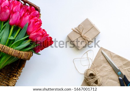 Tulips In Basket Near Wrapped In Craft Paper Gift. Preparation For Celebration. International Women Day, Anniversary. Birthday. Date. Wedding