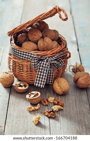 Walnuts in wicker basket on wooden background