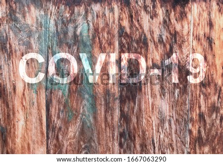 COVID-19 lettering on old wooden wall background. Covid-19 coronavirus concept background Royalty-Free Stock Photo #1667063290