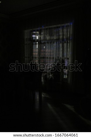Silhouette of a man standing at a window inside the room. Dark mood conceptual image