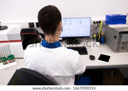 Young scientist sitting at the table with computer and digital tablet stock photo