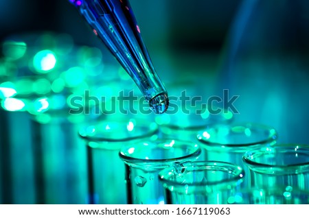 Pipette adding fluid to one of several test tubes, medical abstract background. Royalty-Free Stock Photo #1667119063