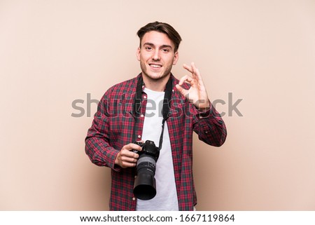 Young caucasian photographer man isolated cheerful and confident showing ok gesture.