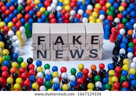 fakenews text on wooden cubes, surrounded by wooden figurines in several colours Royalty-Free Stock Photo #1667124106