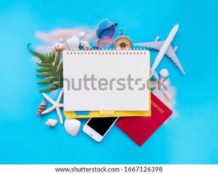 Flat lay, Travel planning concept, notebook, model plane, smartphone and passport on blue background with blank space for text.