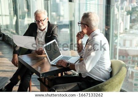 Two Senior businessman couple meeting in co working space at skyscraper lounge or office Royalty-Free Stock Photo #1667133262