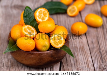 Top view of bunch of fresh kumquats in the organic food market. Some kumquats is cutted. Royalty-Free Stock Photo #1667136673