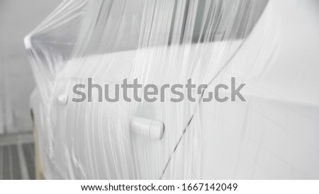 White car is standing in a spray booth covered with a transparent film. Ready to paint Royalty-Free Stock Photo #1667142049