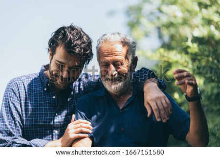 An adult hipster son and senior father at home, talking and smiling with family together, social distancing lockdown and work from home concept Royalty-Free Stock Photo #1667151580
