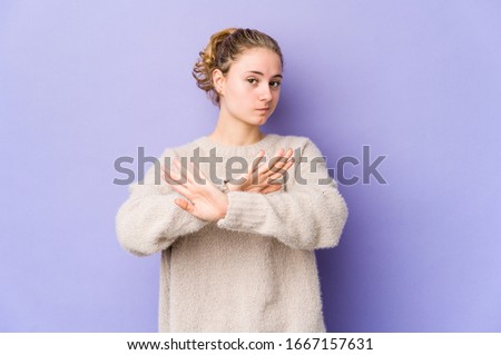 Young caucasian woman on purple background doing a denial gesture