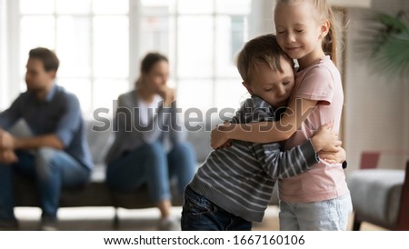 Stressed little girl embracing smaller brother, overcoming parents argue divorce together. Unhappy frustrated kids siblings suffering from family quarrels, misunderstanding of father and mother. Royalty-Free Stock Photo #1667160106