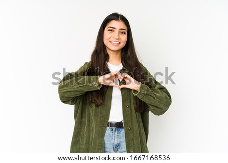 Young indian woman isolated on purple background smiling and showing a heart shape with hands.