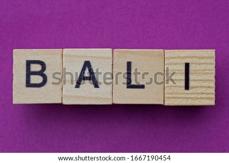 brown word bali from small wooden letters on a red table