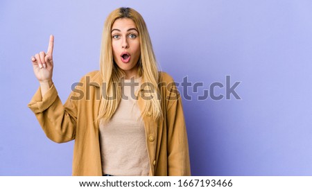 Young blonde woman isolated on purple background having some great idea, concept of creativity.
