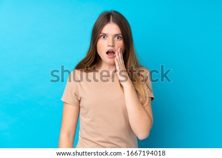 Ukrainian teenager girl over isolated blue background with surprise and shocked facial expression