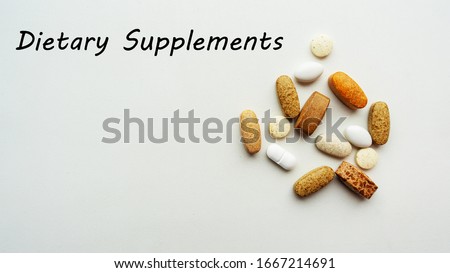 Dietary supplement pills and tablets pile on white background.