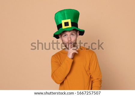 Attractive young guy with a big green hat on a yellow background