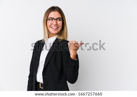 Young business caucasian woman points with thumb finger away, laughing and carefree.