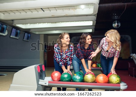 Three funny attractive girlfriends take bowling balls