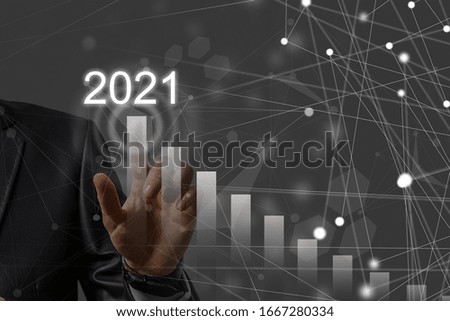 Man's hand pointing graph of success in 2021 year. Growing business concept