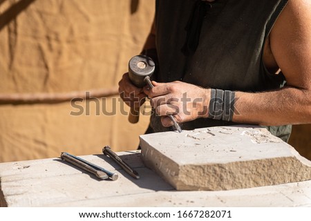 stonemason working with his tools, focused in the foreground with medieval attire

 Royalty-Free Stock Photo #1667282071