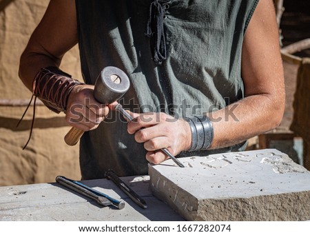 stonemason working with his tools, focused in the foreground with medieval attire

 Royalty-Free Stock Photo #1667282074