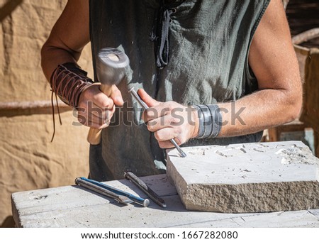 stonemason working with his tools, focused in the foreground with medieval attire

 Royalty-Free Stock Photo #1667282080
