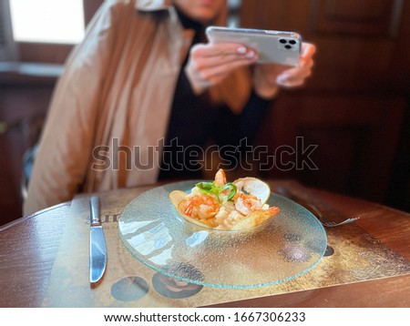girl photographs a restaurant dish on a smartphone