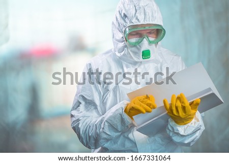 Female epidemiologist in protective clothing reading research report in virus quarantine, medical professional working Royalty-Free Stock Photo #1667331064