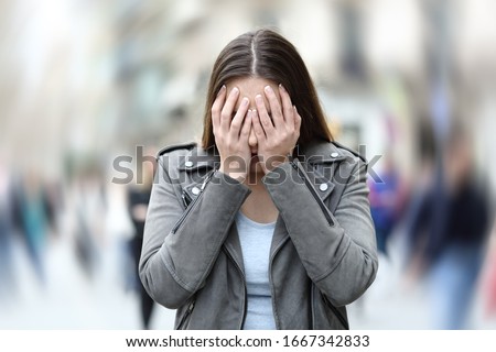 Front view of a woman suffering social anxiety attack on city street Royalty-Free Stock Photo #1667342833