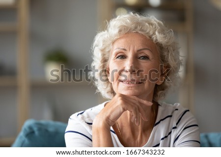 Portrait of happy elderly 50s gray-haired woman look at camera showing positive and optimism, headshot picture of smiling old middle-aged 60s grandmother feel overjoyed satisfied relaxing at home