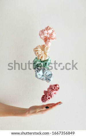 Lot of floating Colorful silk Scrunchies on womas hand isolated white. Hairdressing tools and accessories. Hair Scrunchies, Elastic HairBands, flying or falling Scrunchie Hairband for girl. copy space Royalty-Free Stock Photo #1667356849