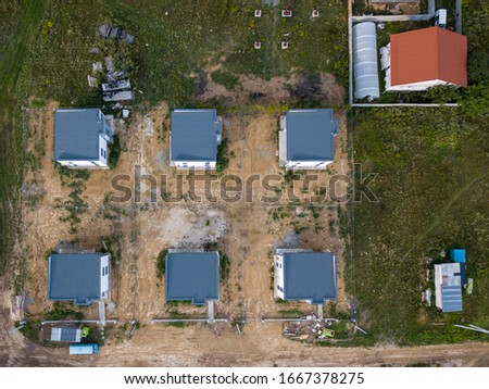 Construction of cottage houses in a vacant lot with an access dirt road Aerial view