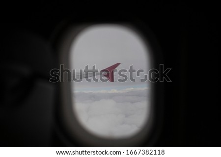 Airplane wing shot through the porthole. During the flight. High above the clouds. The wing of a passenger plane. Taking pictures from an aircraft of an airliner.