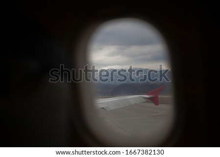 Airplane wing shot through the porthole. During the flight. High above the clouds. The wing of a passenger plane. Taking pictures from an aircraft of an airliner.