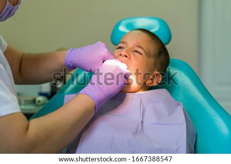 Dentists with a patient during a dental intervention to boy. Dentist Concept. At dentist's office