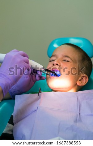 Dentists with a patient during a dental intervention to boy. Dentist Concept. At dentist's office. vertical photo