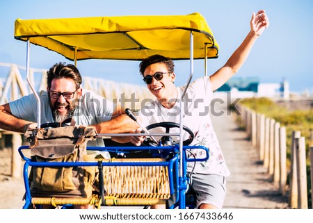 Father and son friends have fun together laughing a lot on a vehicle bike - crazy mixed generations people enjoy the vacation and life - craziness happiness with young men in outdoor leisure activity