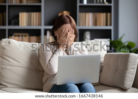 Stressed middle aged woman hiding face with both hands. Depressed senior older grandmother crying after reading bad news message on laptop. Unhappy mature elderly lady feeling desperate alone at home. Royalty-Free Stock Photo #1667438146