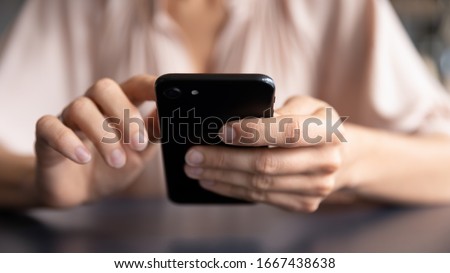 Close up front view young woman holding smartphone, typing message, chatting with friends in social networks. Female client using application on mobile phone, shopping online, web surfing, order food.