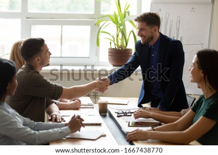 Happy male colleagues shake hands get acquainted greeting at team meeting in office, smiling man coworkers handshake after successful negotiation or presentation at briefing, acquaintance concept